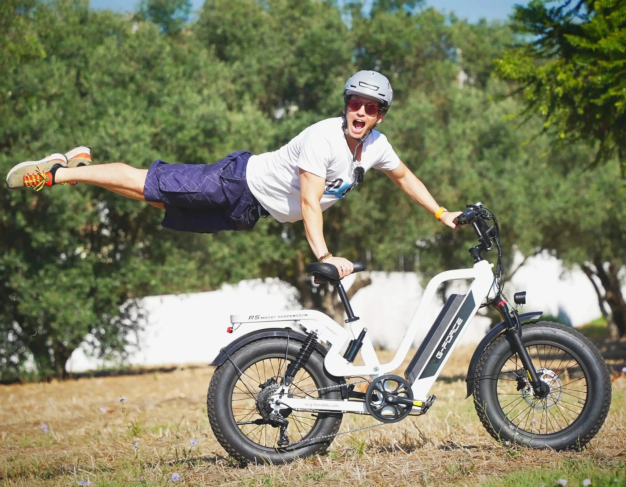 Man lifts the front wheel of the G-force RS ST electric bike on grass, demonstrating its robust outdoor capability. 